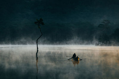 Man in boat on lake during foggy weather