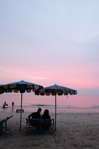 Chairs on beach against clear sky during sunset