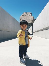 Portrait of boy standing against built structure