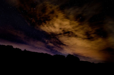 Low angle view of silhouette mountain against sky at night