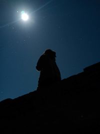 Low angle view of silhouette man standing against sky at night