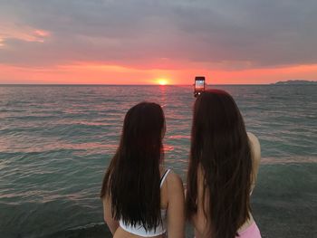 Rear view of women at beach during sunset