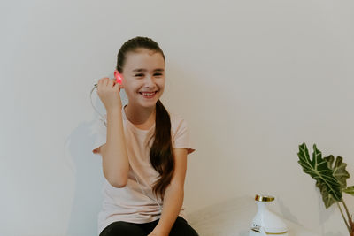 Portrait of young woman standing against wall