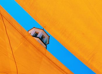 Low angle view of orange building against clear blue sky