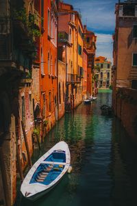 Boats moored in canal amidst buildings in city