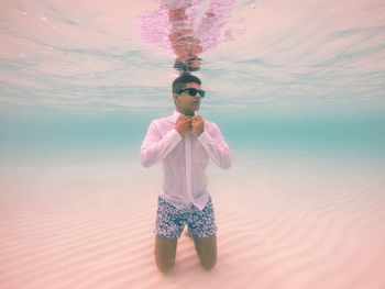 Young man adjusting bow tie underwater