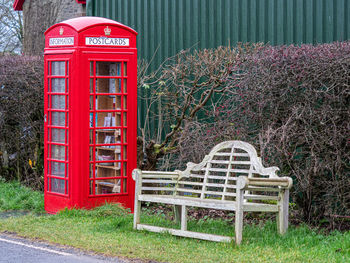 Red telephone booth on grass against plants