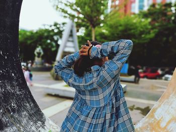 Young man standing by tree in city