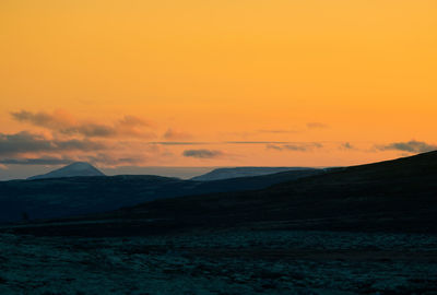 Scenic view of silhouette mountains against orange sky