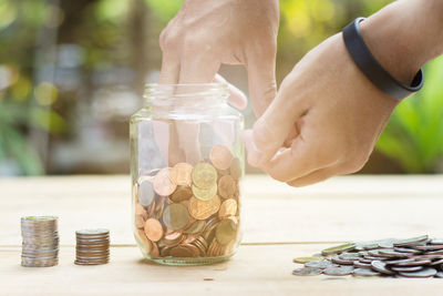 Cropped image of man removing coins from jar