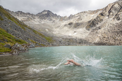 Man dives in for swim in upper reed lake, talkeetna mountains, alaska