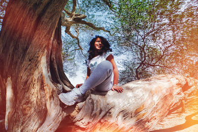 Young woman sitting on rock in forest