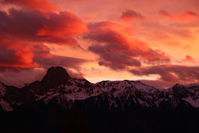 Scenic view of snowcapped mountains against orange sky