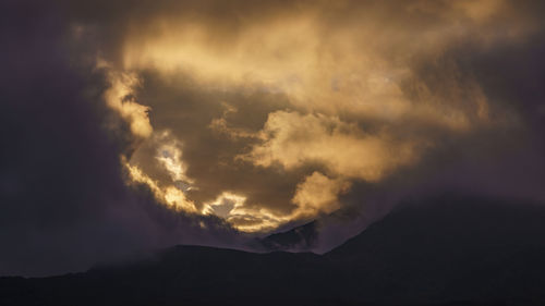 Low angle view of storm clouds over mountain