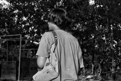 Rear view of woman standing against trees