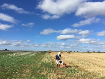 Father and daughter standing on field against sky