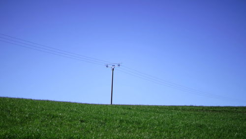 Electricity pylon on field against clear sky