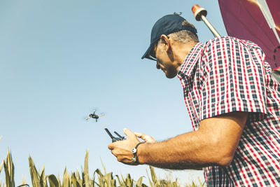 Man flying drone while standing against clear sky