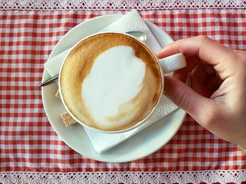 Close-up of hand holding tea cup on table