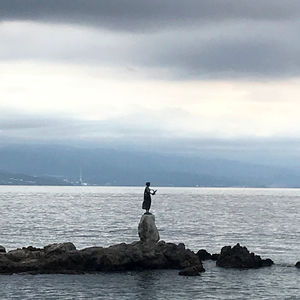 Statue on rock by sea against sky