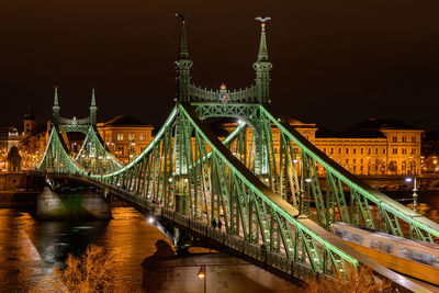 Illuminated bridge over river at night