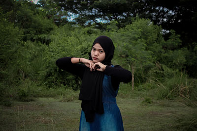 Portrait of young woman standing on field