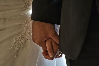 Midsection of wedding couple holding hands