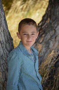 Portrait of boy leaning on tree at cherry creek state park