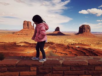 Full length of woman standing on rock against sky