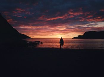 Silhouette of man standing on beach at sunset