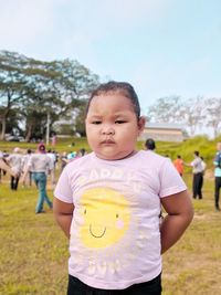 Cute girl standing at park against sky