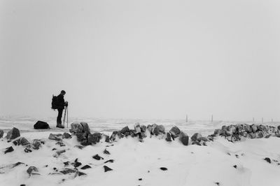Hiker with tripod on snow covered field