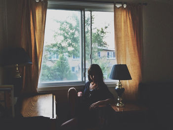 A young girl sitting alone in a dark living room