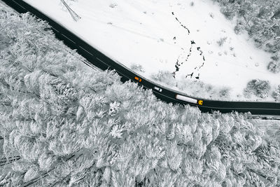 Aerial view of cars and truck on road by winter forest