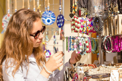Girl wearing sunglasses buying bracelets at market stall