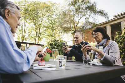 Senior people using mobile phones at table of outdoor restaurant