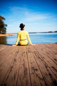 Rear view of woman sitting on pier