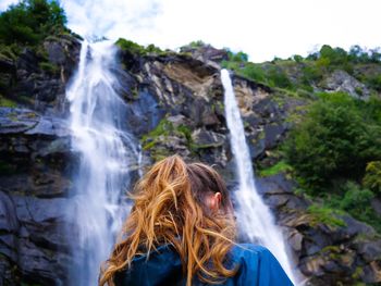Rear view of woman against waterfall in forest
