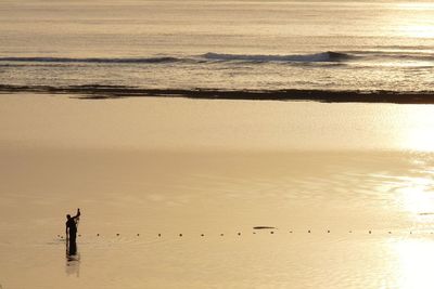 Silhouette people on beach against sky during sunset