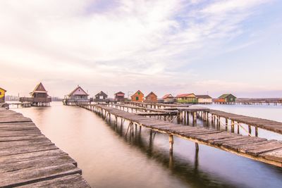 Pier over sea by buildings against sky