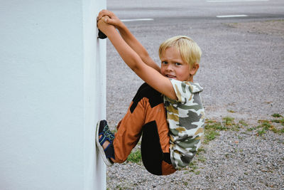 Boy looking away while standing against wall