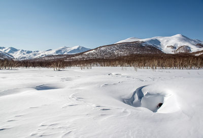 Snow covered field by mountains against sky at nalychevo nature park