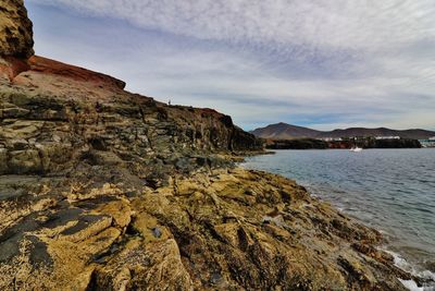 Scenic view of sea by cliff against sky