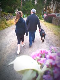 Rear view of woman with dog on road