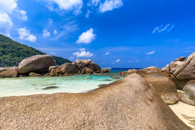 Rocks on beach against blue sky