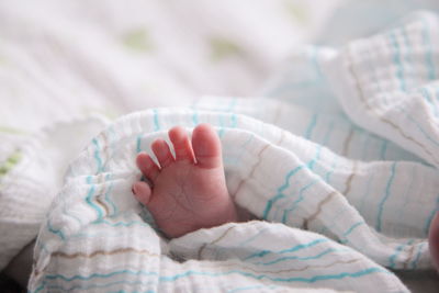 Low section of baby sleeping on bed