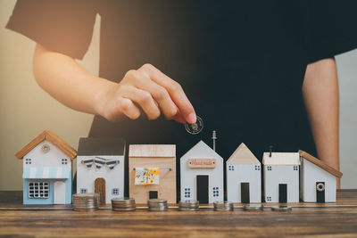 Cropped hand of man holding model house on table