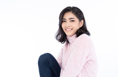 Portrait of smiling young woman against white background