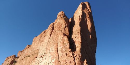 Low angle view of rock formation against clear blue sky