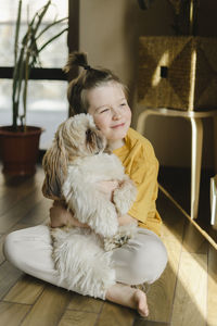 Smiling boy embracing dog at home